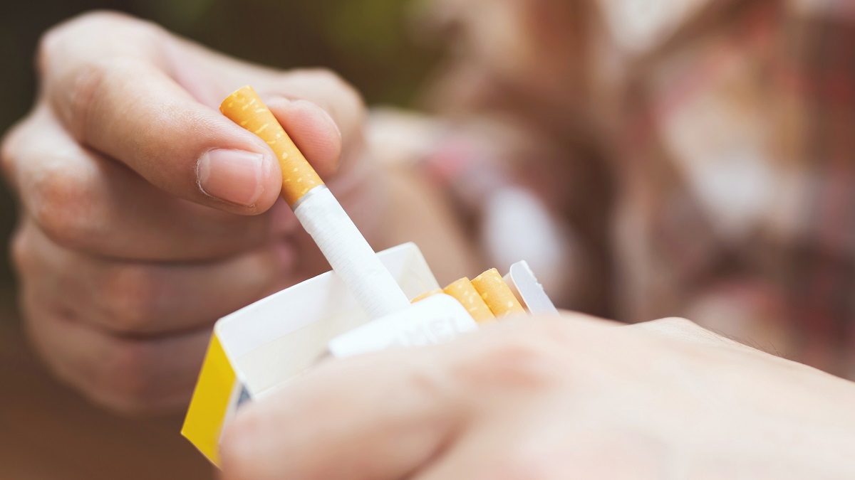Um homem segurando um cigarro apagado em uma mão e uma garrafa de água na outra, simbolizando a luta para parar de fumar.